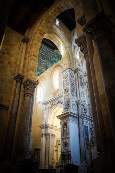  The image depicts the interior of a grand cathedral, showcasing its architectural beauty. The foreground features tall, ornate columns with intricate carvings, leading the eye towards the central archway. The archway is adorned with detailed sculptures and reliefs, enhancing the sense of grandeur. The walls are made of light-colored stone, with some areas showing signs of wear, adding to the historical ambiance. Sunlight filters through the windows, casting a warm glow and creating a contrast between light and shadow. The ceiling is supported by a network of beams, and a green protective netting is visible, suggesting ongoing restoration work. The overall atmosphere is one of reverence and historical significance.</p>

<p>Provided by @altbot, generated privately and locally using Ovis2-8B
