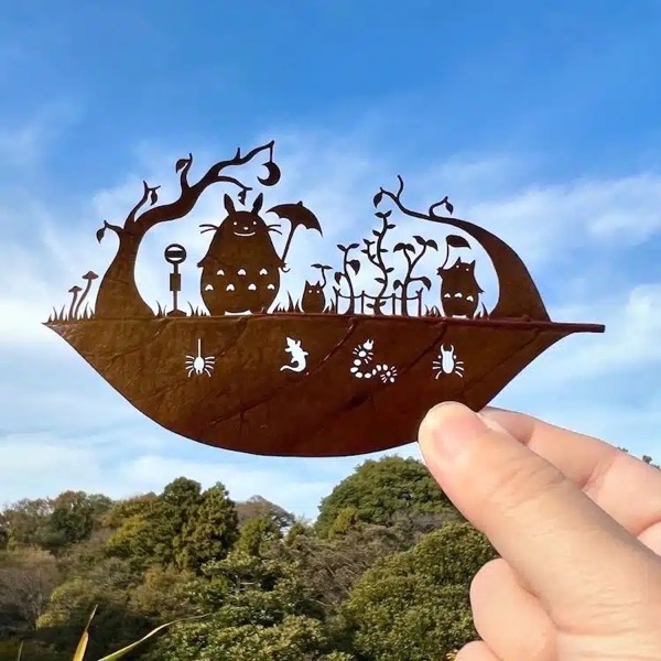  The image features a hand holding a rust-colored metal cutout shaped like a leaf. The cutout depicts a scene from the animated film My Neighbor Totoro, with characters such as Totoro, a small creature, and a tree with a crescent moon hanging from its branches. The scene includes various elements like mushrooms, plants, and insects, all intricately cut out to create a silhouette effect. The background shows a clear blue sky with some clouds and a lush green landscape, providing a natural contrast to the metal cutout. The hand holding the cutout is visible, with fingers gently gripping the leaf-shaped object.</p>

<p>Provided by @altbot, generated privately and locally using Ovis2-8B